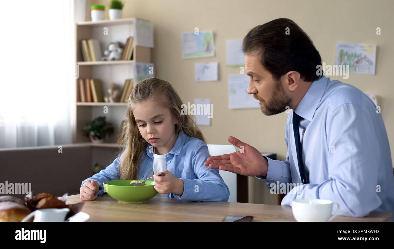 Père strict parlant à la fille dans la cuisine, parent et enfant conflit, famille Banque D'Images