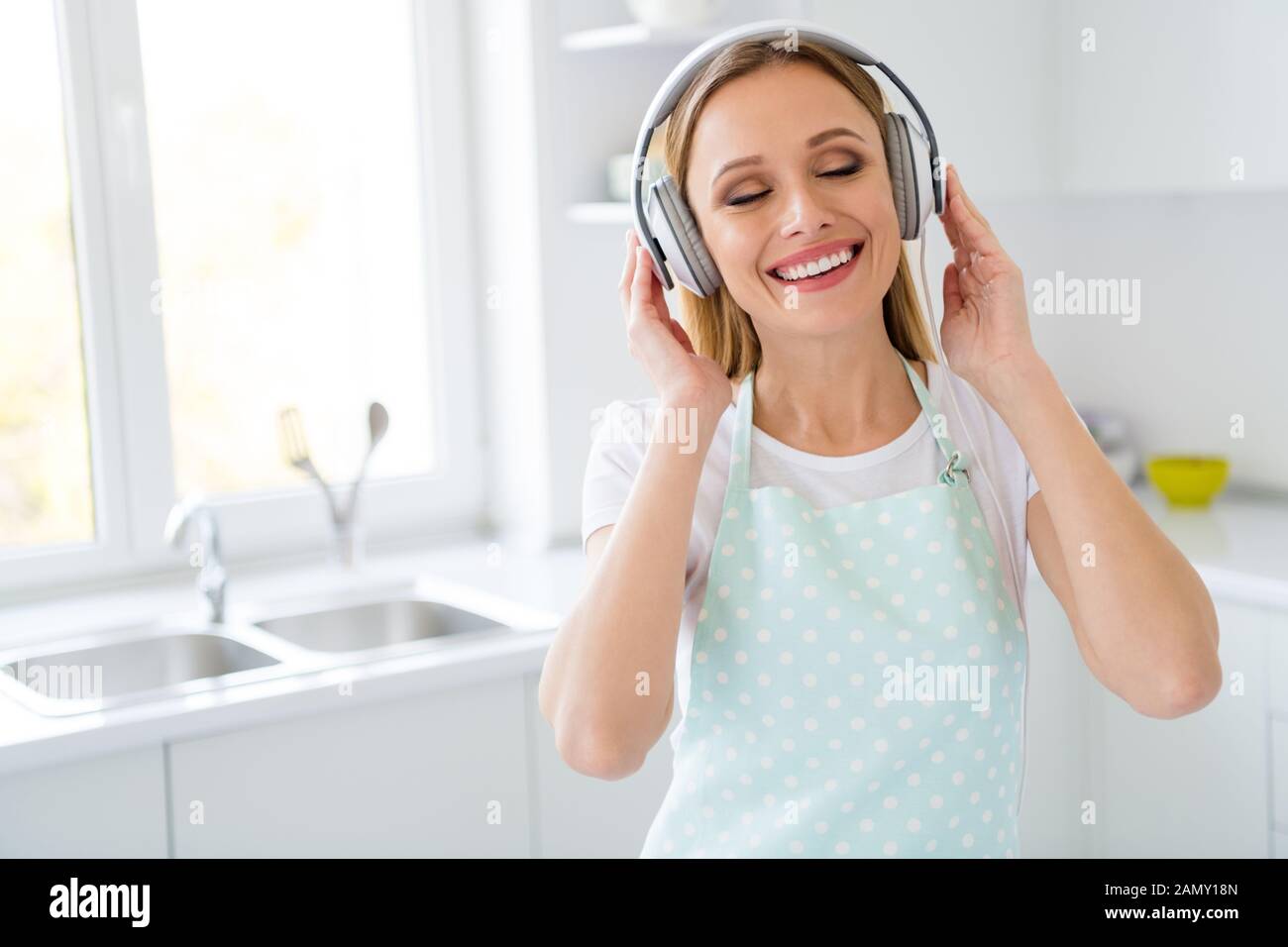 Photo de jolie femme au foyer du matin le week-end de dépenses à l'écoute de la musique à l'aide d'écouteurs moderne agréable mélodie capter l'énergie pour le nettoyage général Banque D'Images