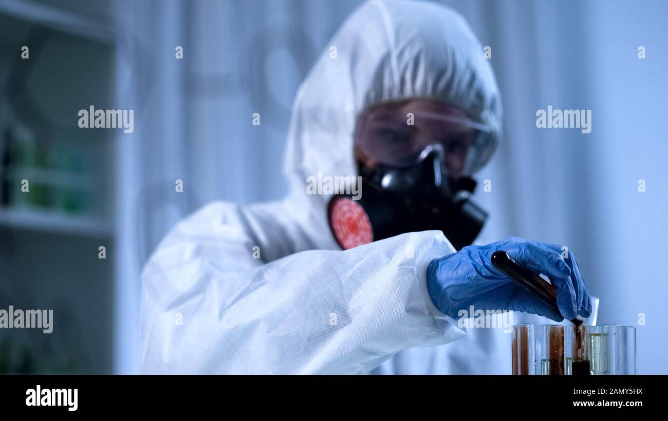 Scientifique qui verse de l'huile minérale dans le tube à essai, production à partir de produits pétroliers Banque D'Images