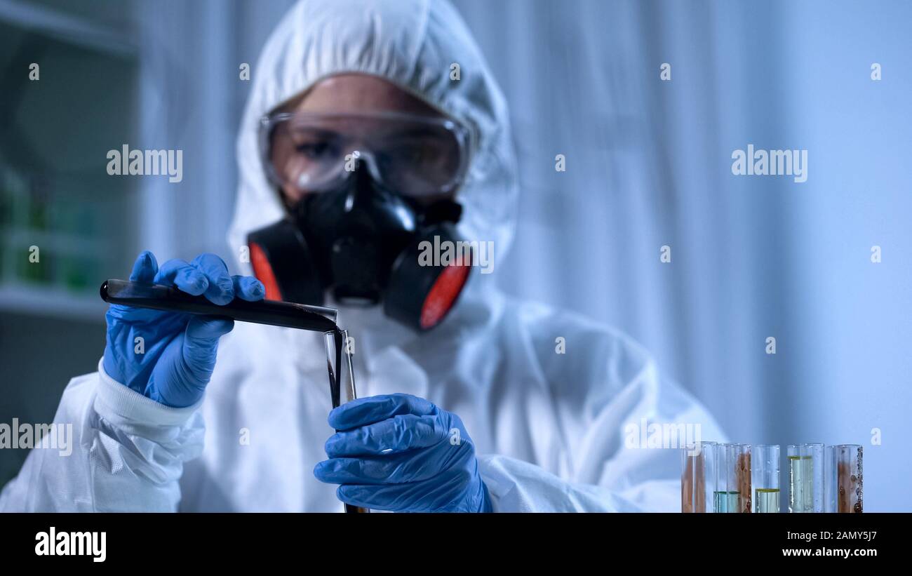 Assistant de laboratoire qui verse de la pétrochimie dans le tube à essai, industrie pétrolière Banque D'Images