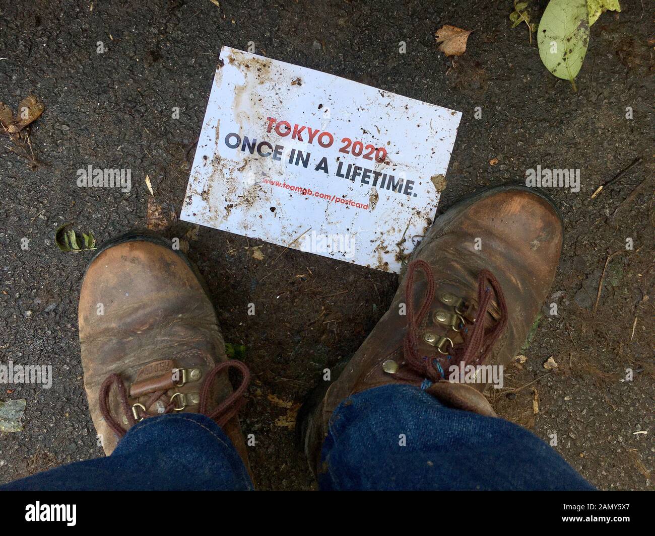 Tokyo 2020 flyer foulé par les bottes boueuses Banque D'Images