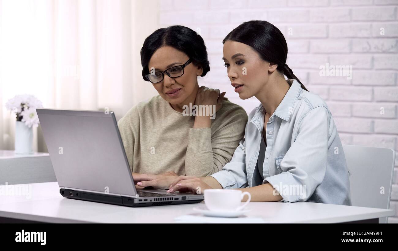 Fille enseignant mère à utiliser l'ordinateur portable, montrant des logiciels utiles, l'alphabétisation informatique Banque D'Images