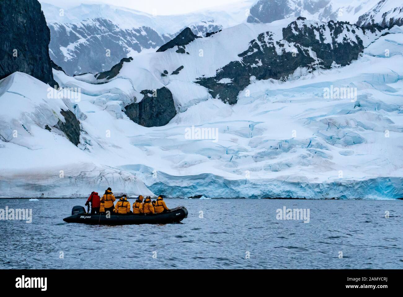 Touristes sur un bateau en caoutchouc dériveur observation des baleines près d'un iceberg. Photographié À Paradise Bay, En Antarctique. Banque D'Images
