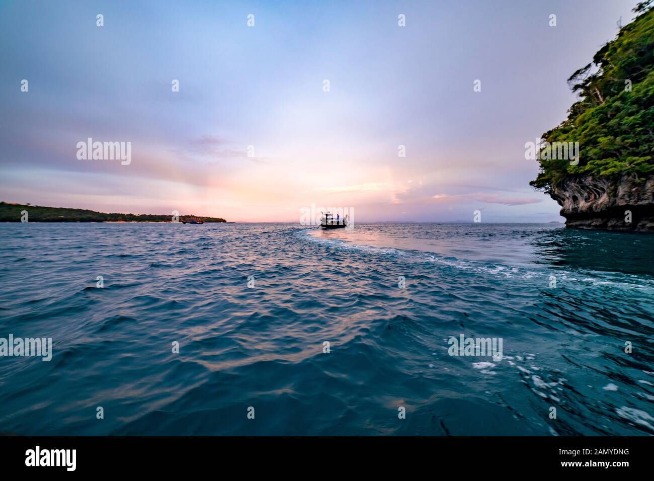 Un bateau naviguant au large pendant la golden hour au large des côtes de la Thaïlande. Banque D'Images