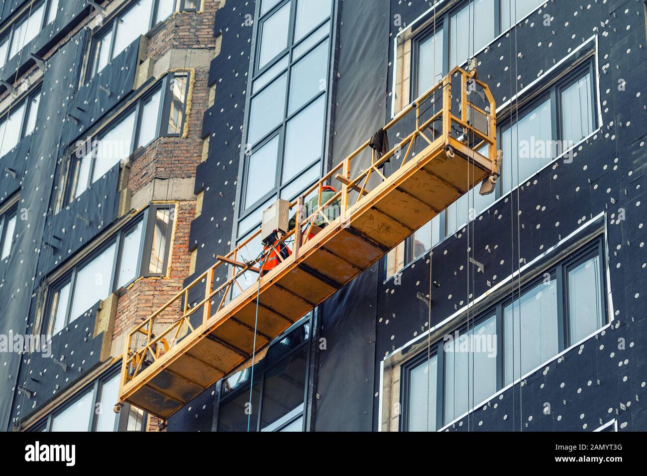 Construction suspendu berceau près de mur de hightower residentaial avec isolation du bâtiment et façade ventilée sur chantier de construction. Engineering Banque D'Images
