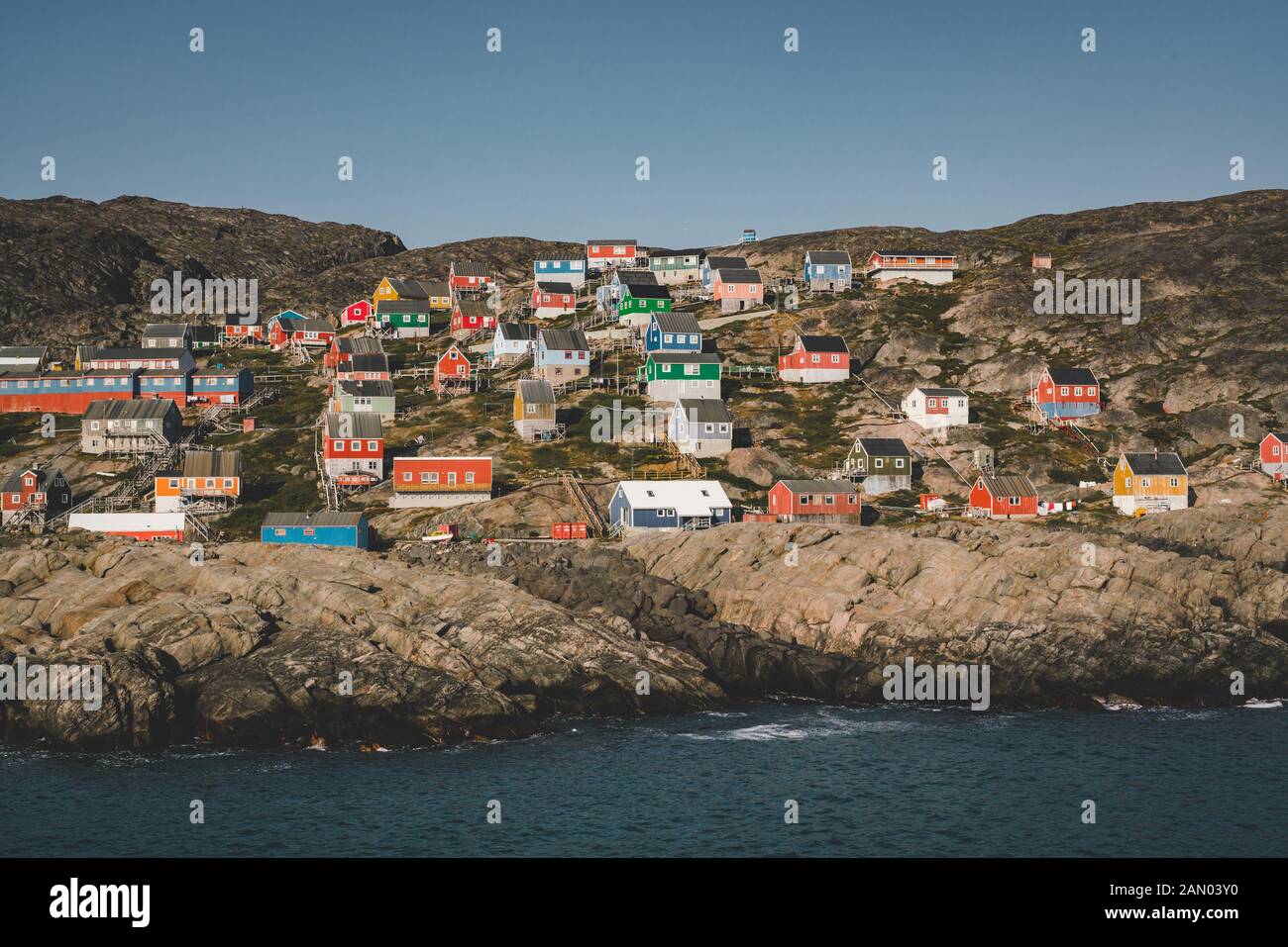 Des maisons colorées parsement les collines de la ville de pêcheurs de Kangaamiut, à l'ouest du Groenland. Icebergs du glacier de Kangia au Groenland nageant avec le ciel bleu Banque D'Images