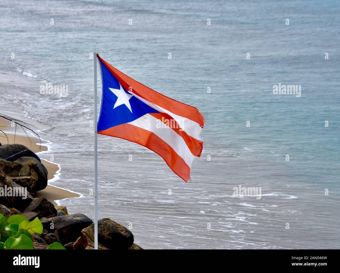 Le drapeau de Porto Rico survole un océan plage de Rincón, PR. Copier l'espace. Banque D'Images
