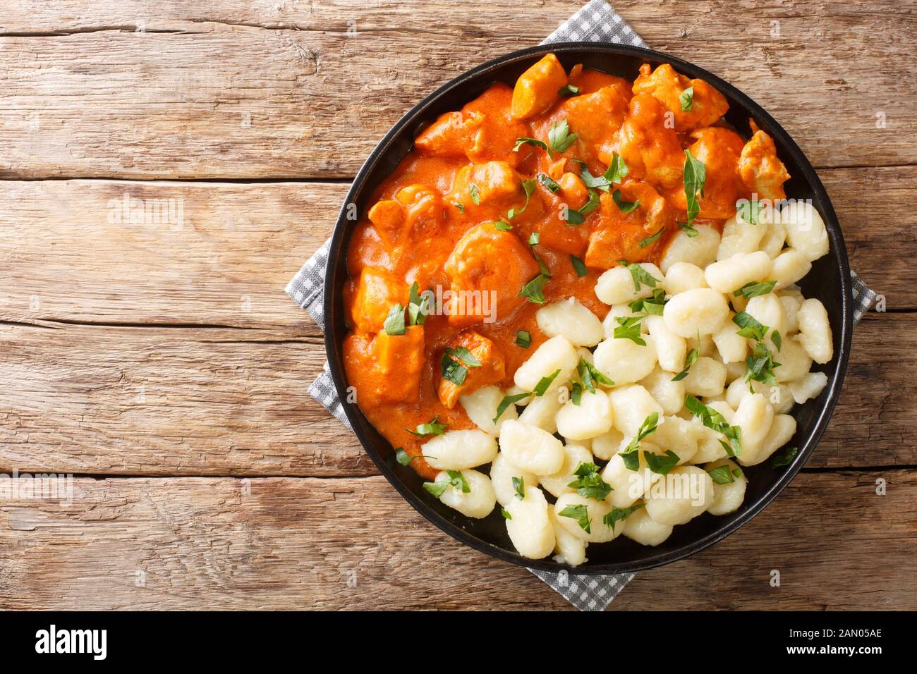 Le paprikash de poulet hongrois présente un poulet braisé tendre et une sauce piquante épicée avec du paprika qui se ferme sur une assiette sur la table. Vue de dessus horizontale Banque D'Images