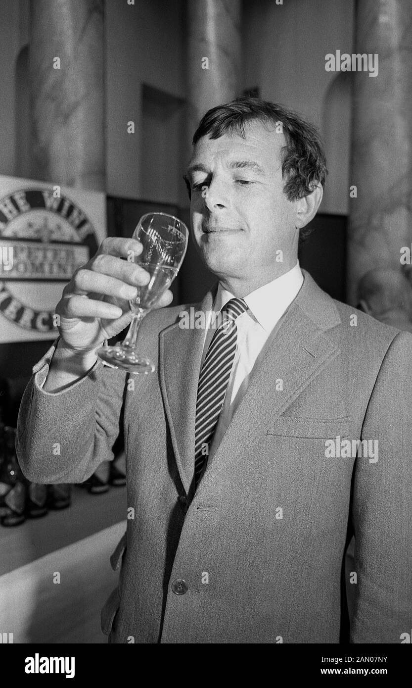 1988, historique, un homme en veste et cravate lors d'une dégustation de vin, tenant un verre de vin blanc et de l'évaluation de sa couleur, England, UK, Banque D'Images