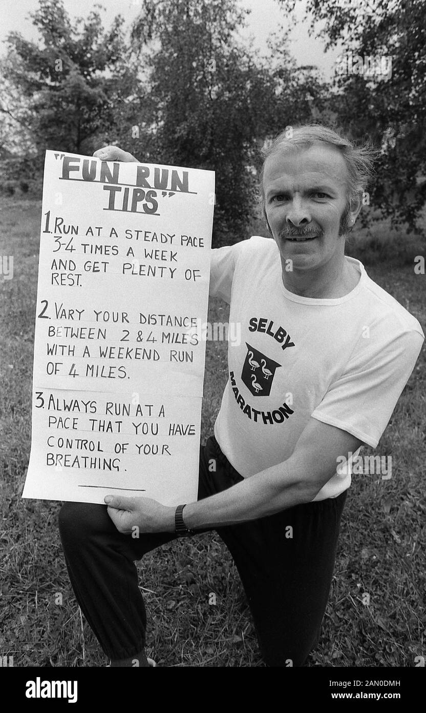 Années 1980, historique, d'un athlète amateur à genoux à la tenue d'un avis écrit à la main sur l'exécution, intitulée "Fun Run Conseils', Angleterre, Royaume-Uni. Banque D'Images