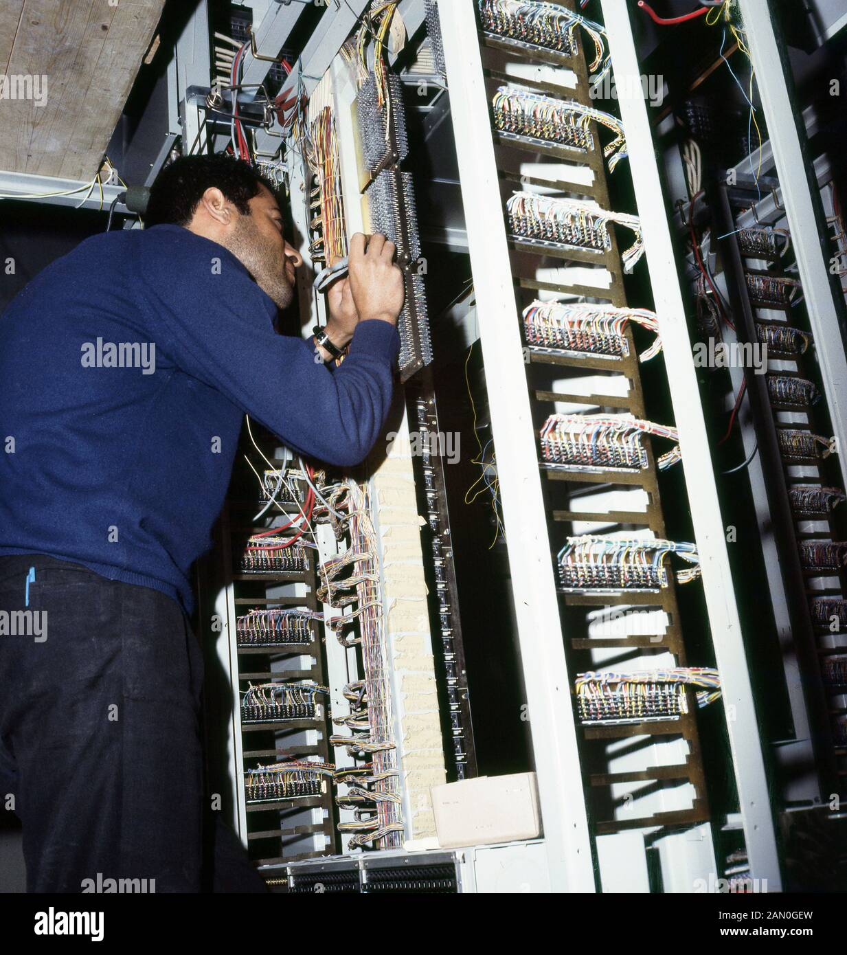 Années 60, historique, un électricien de sexe masculin qui effectue des travaux de câblage ou de câblage dans une installation de télévision, en Arabie Saoudite. Banque D'Images