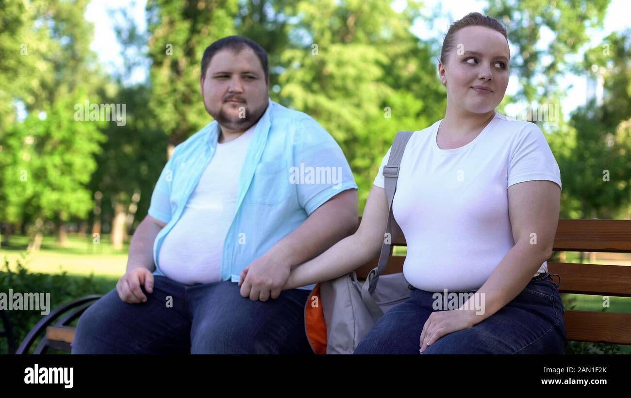 Couple obèse à la première date, homme tenant tendement la main de petite amie, l'amour et les soins Banque D'Images