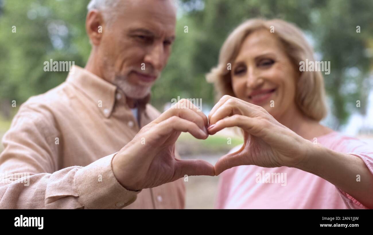 Smiling couple montrant coeur signe, symbole d'Amour, mariage heureux, de l'affection Banque D'Images