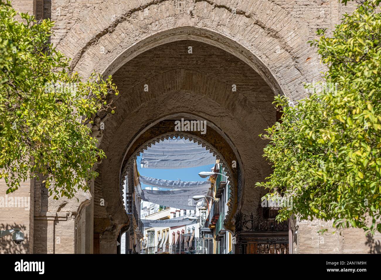 Les multiples arcs en fer à cheval de la Puerta del Perdon, dans la Cathédrale de Séville, menant à des bâtiments et des parasols de la Calle Hernando Colón. Banque D'Images
