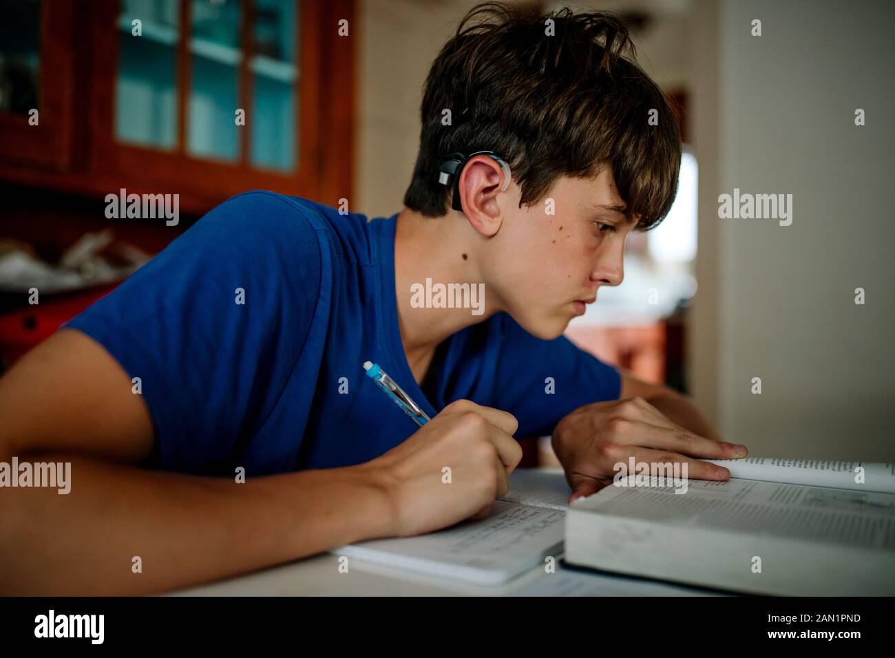garçon de 15 ans avec implant cochléaire pour faire ses devoirs Banque D'Images