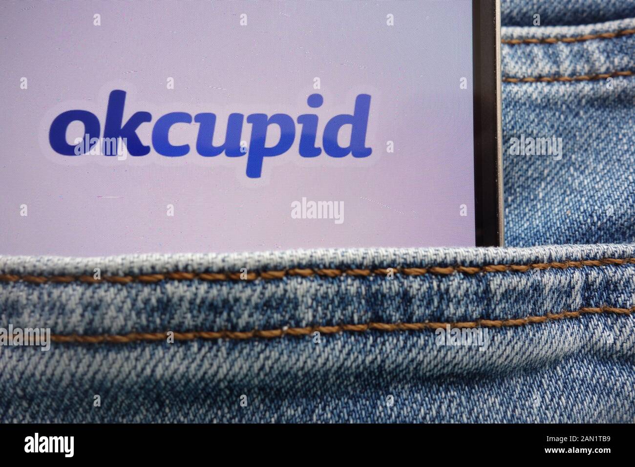 Okcupid logo affiché sur smartphone caché dans la poche de jeans Banque D'Images