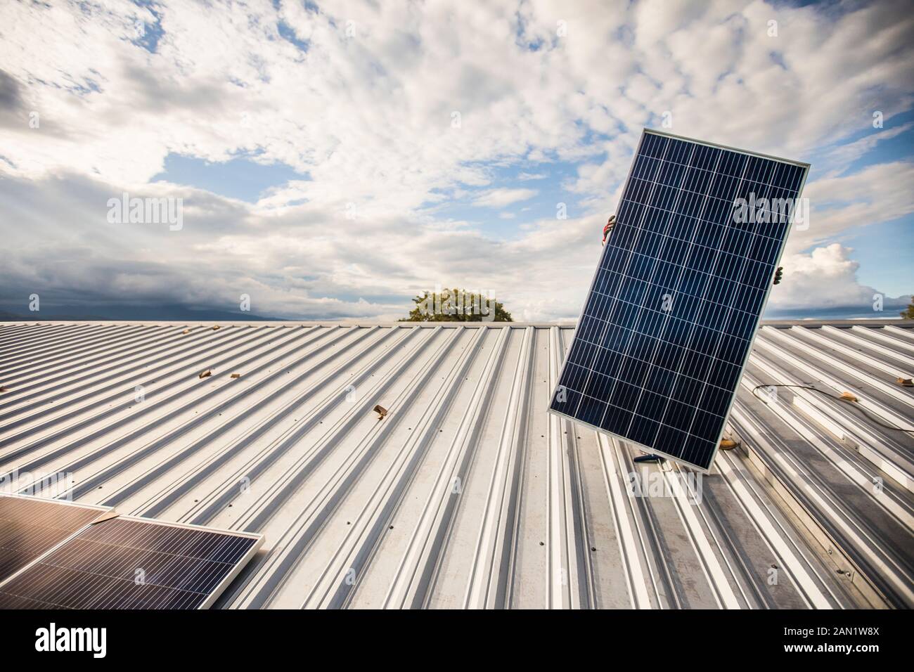 Faible angle de la personne cachée transportant le panneau solaire sur le toit. Banque D'Images