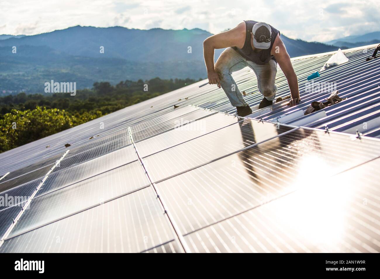 L'employé travaille avec soin pour fixer les panneaux solaires sur le toit du bâtiment. Banque D'Images