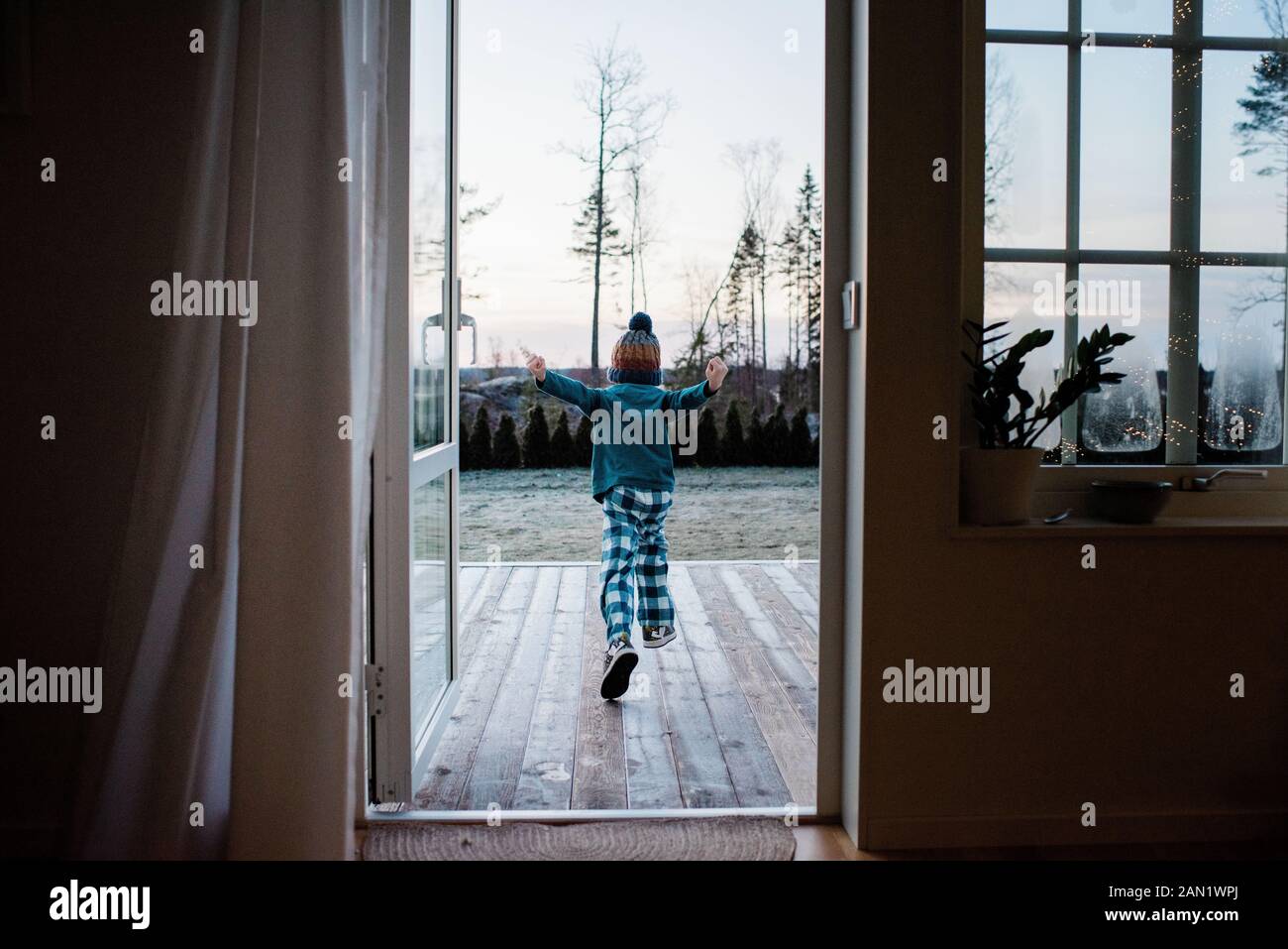 un jeune garçon qui court à l'arrière pour jouer dehors en hiver Banque D'Images