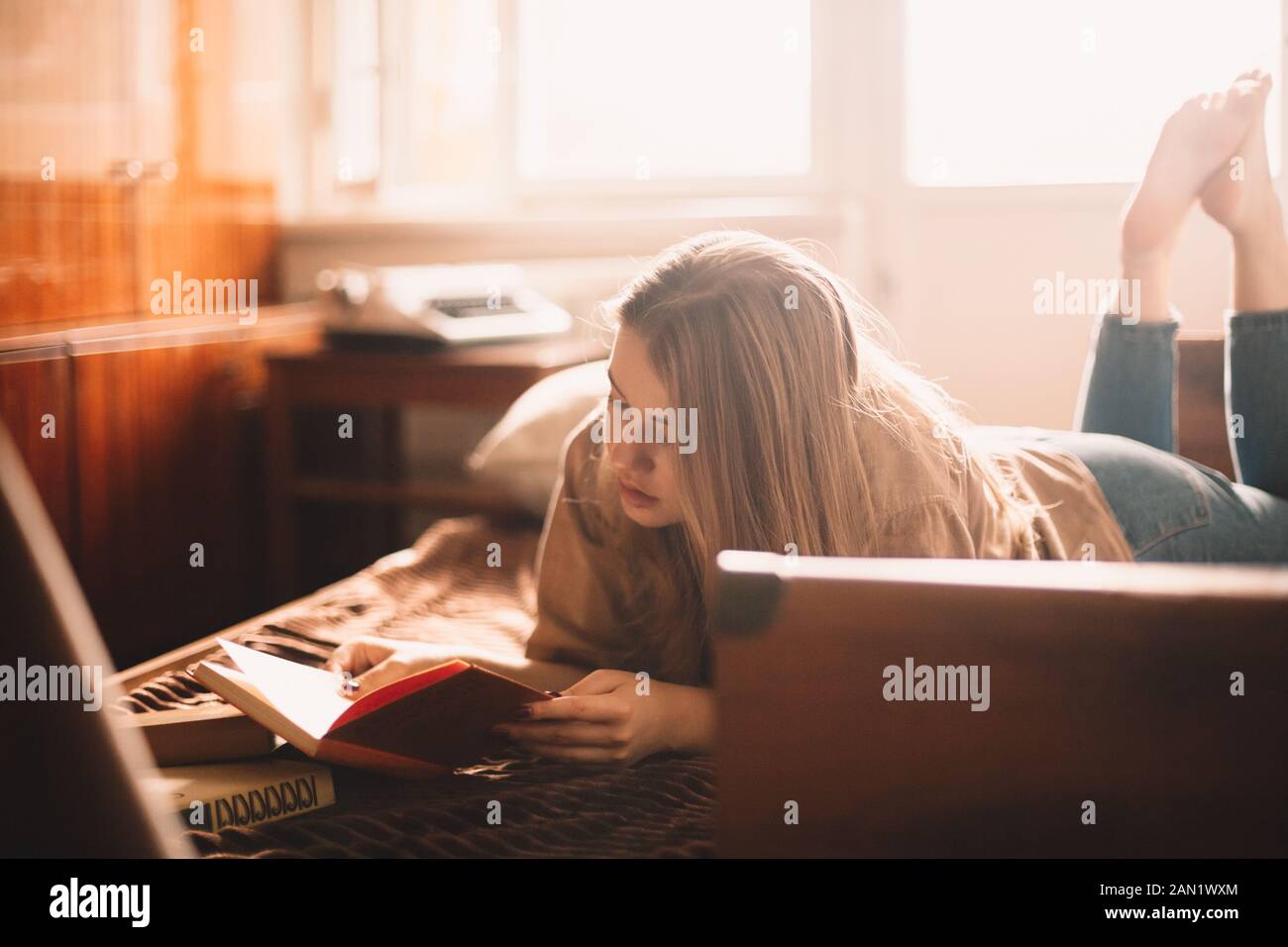 Jeune femme lisant un livre en étant couché sur le lit à la maison Banque D'Images