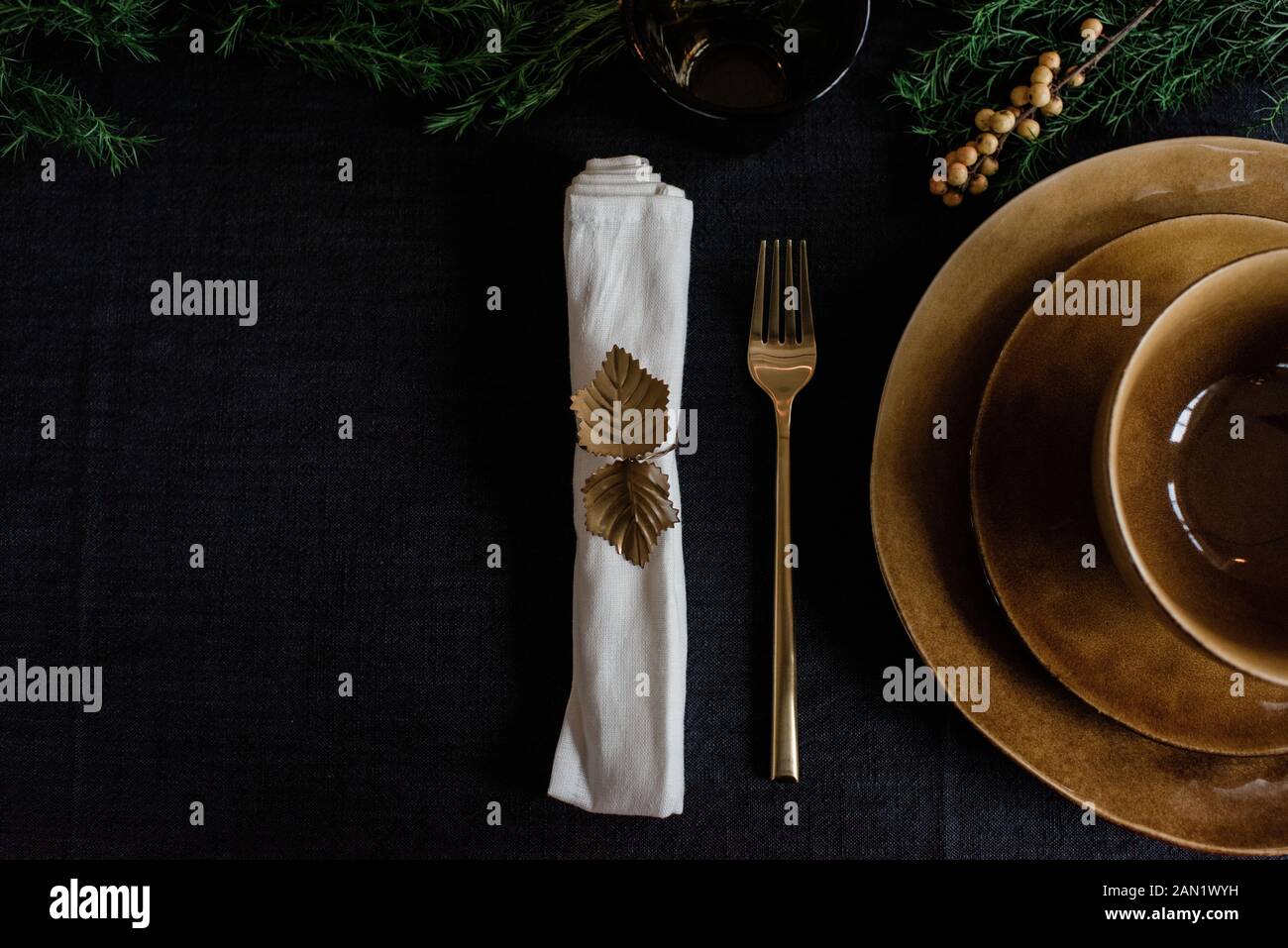 porte-serviette doré, assiettes et fourchette sur table décorée Banque D'Images