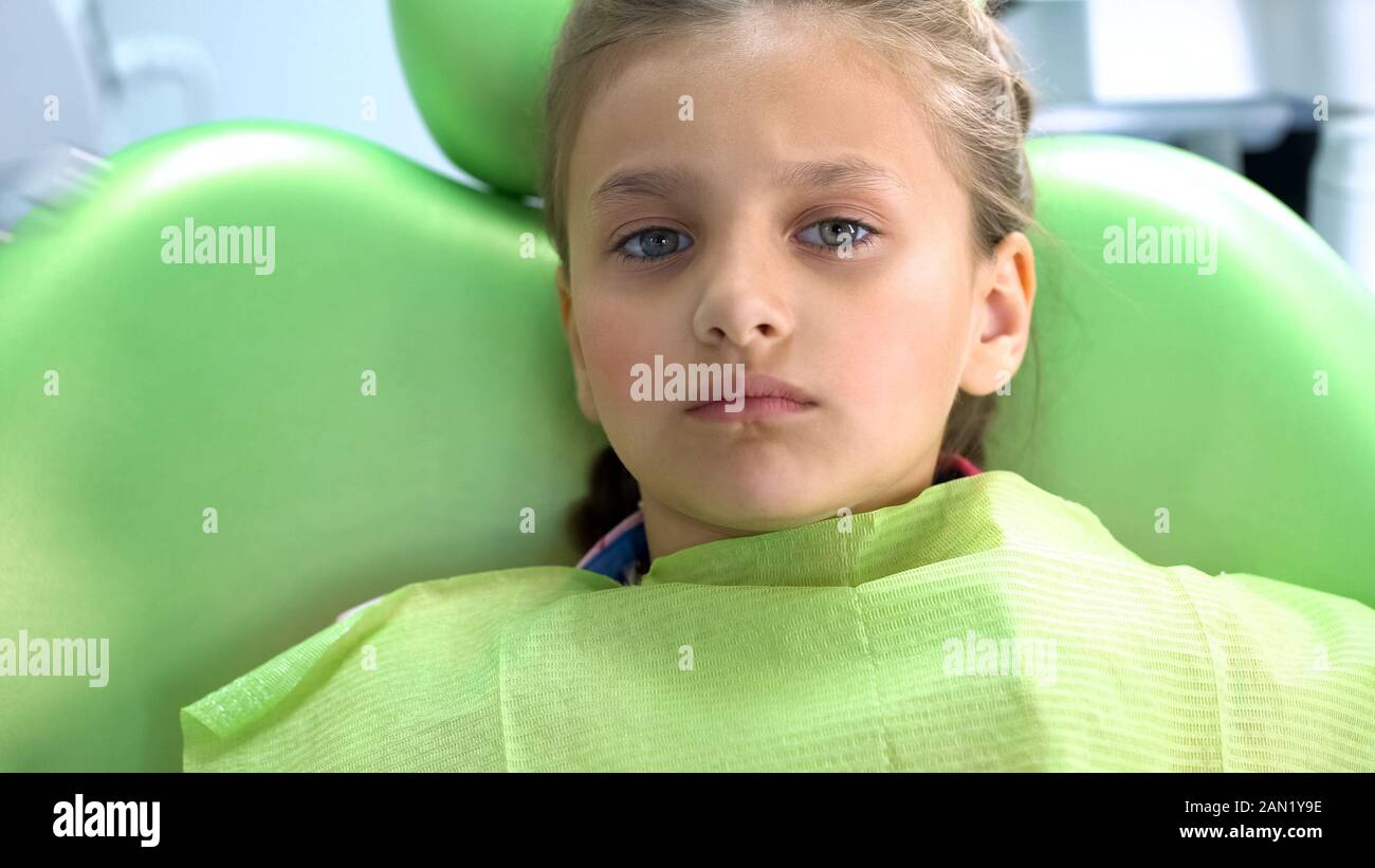 Peur preschool girl fronce et siège dans l'attente pour la procédure président dentiste Banque D'Images