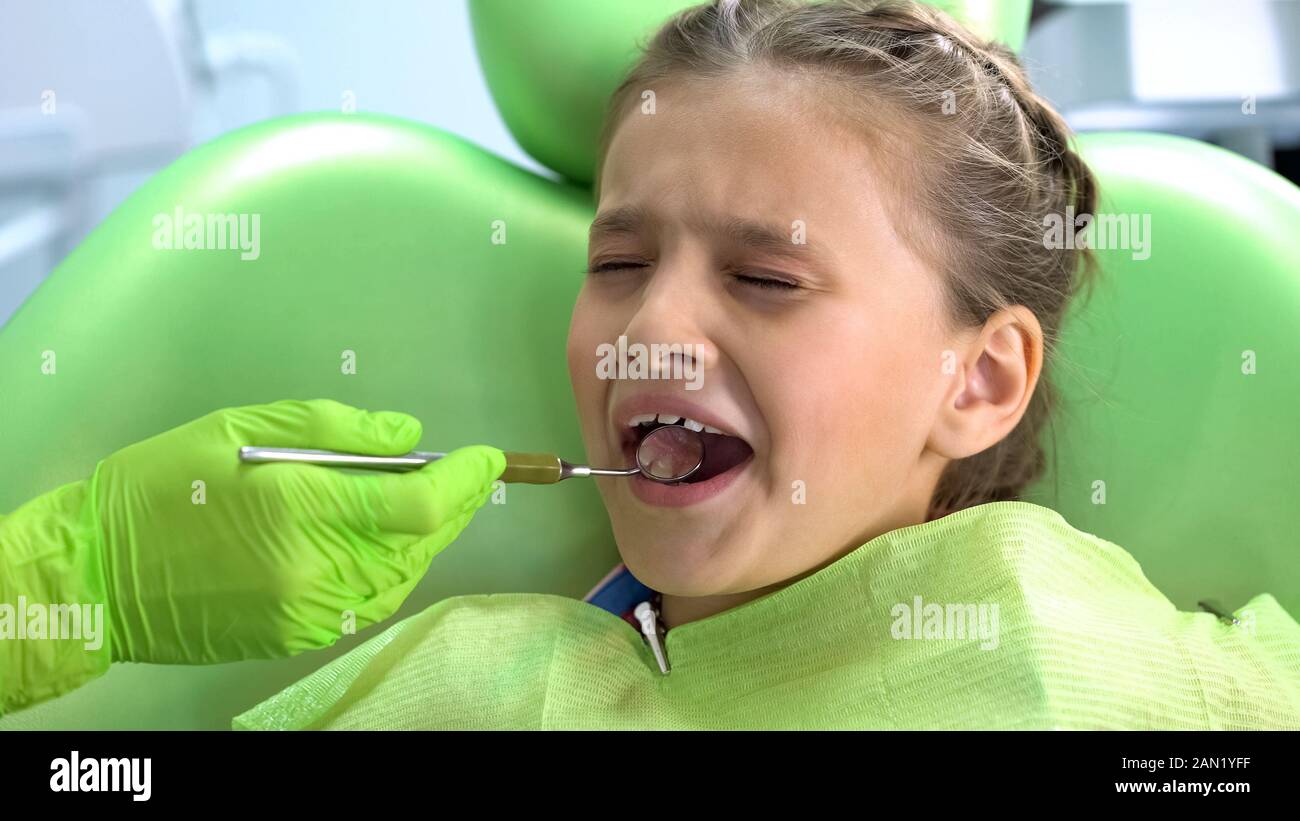 Cute girl préscolaire peur des soins dentaires checkup avec miroir de la bouche, la peur enfantine Banque D'Images