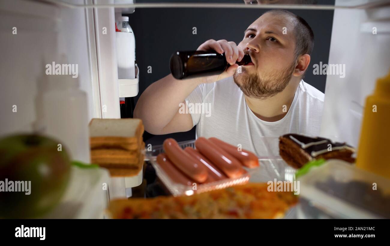 L'homme obèse bouteille de bière potable secrètement du frigo la nuit, l'échec de régime Banque D'Images