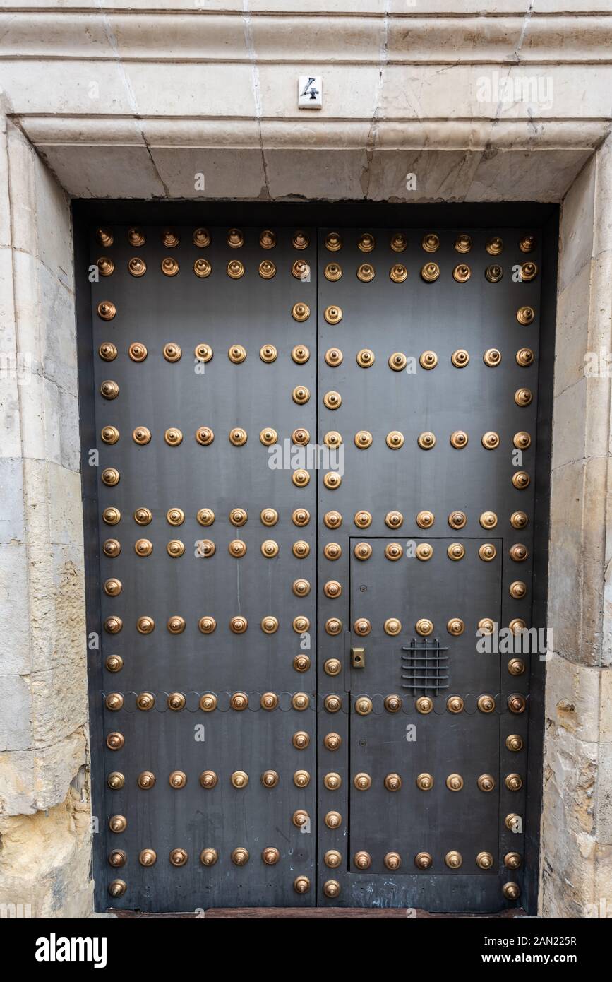 Une porte cloutée en laiton à un bâtiment dans une rue latérale de Séville. Banque D'Images