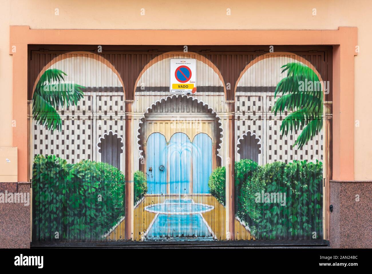 Jardin traditionnel de la cour de Mudejar avec étang, fontaine et palmiers peints sur la porte de garage d'une maison sur la Plaza San Juan de la Palma, Séville. Banque D'Images