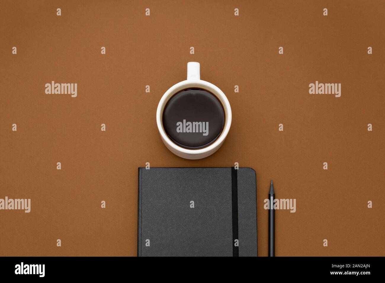Ordinateur portable noir, crayon, tasse de café sur la table, fond marron minimalisme, espace de travail avec copie espace. Banque D'Images