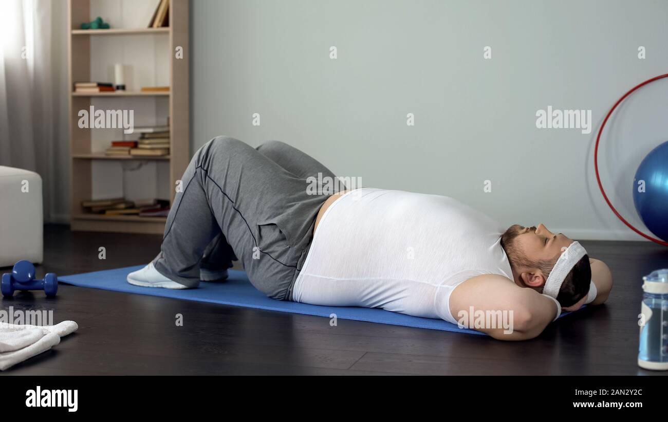 Jeune homme surdimensionnés faisant des craquements, des exercices abdominaux, le pompage des muscles faibles Banque D'Images