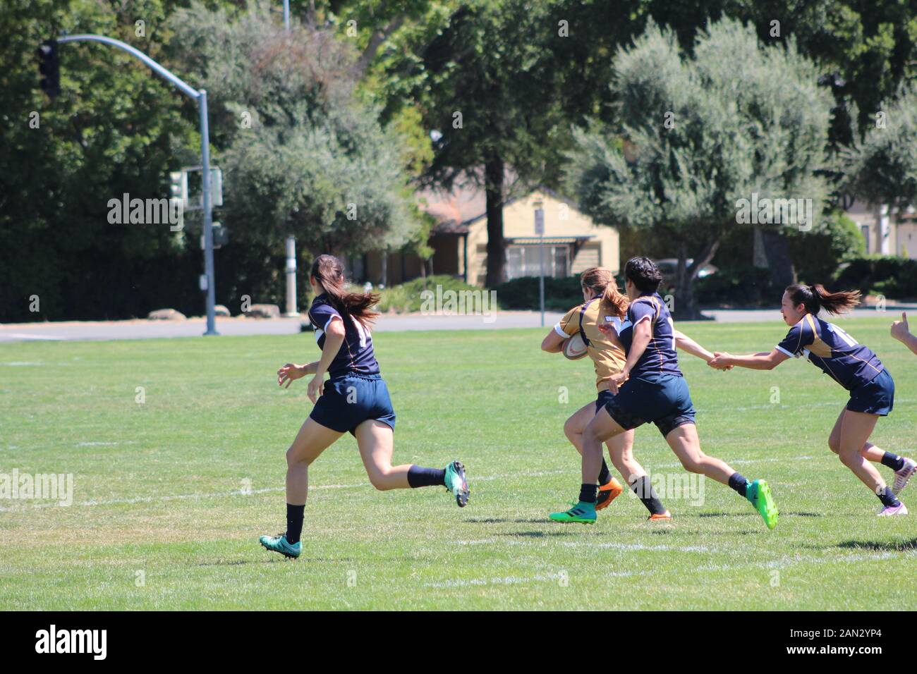 Les femmes d'âge collège à jouer au rugby dans un champ ouvert, en passant le ballon et d'exécution. Banque D'Images