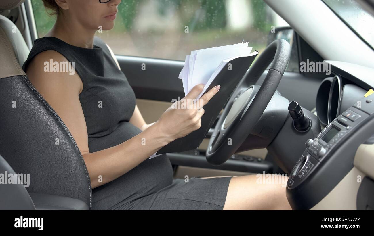 Avocat enceinte la lecture de documents de travail en auto, pendant le troisième trimestre Banque D'Images