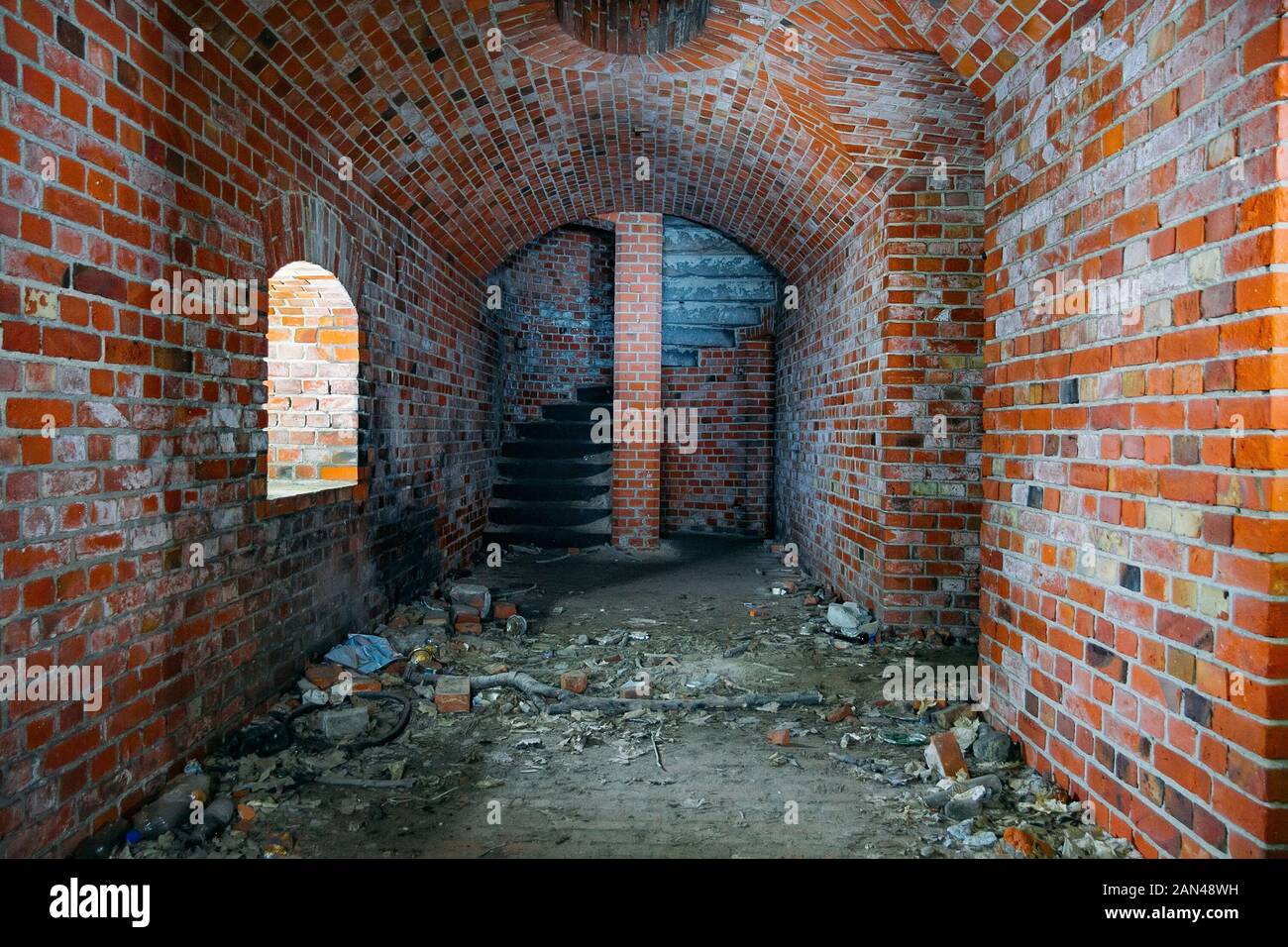 Couloir voûté de l'ancienne forteresse prussienne de brique rouge, se terminant par un escalier en colimaçon. Banque D'Images