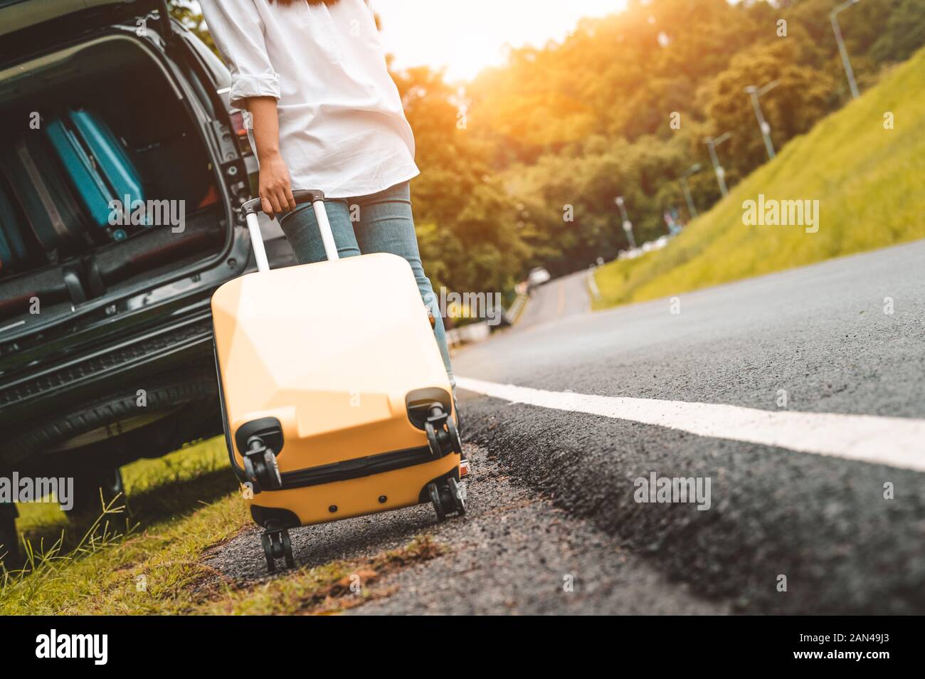 Vue arrière de valise bagage valise jaune faisant glisser seul road trip pour le chargement en voiture SUV. Les modes de vie des gens et de vacances. Nature et su Banque D'Images
