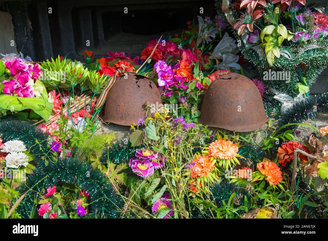 Old rusty endommagé des soldats soviétiques se trouvent sur des casques et des couronnes de fleurs Banque D'Images