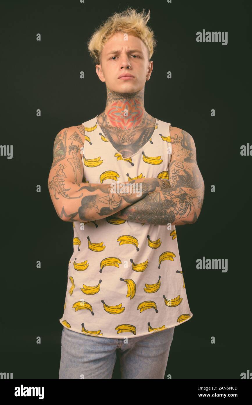 Beau jeune homme rebelle aux cheveux blonds sur fond noir Banque D'Images