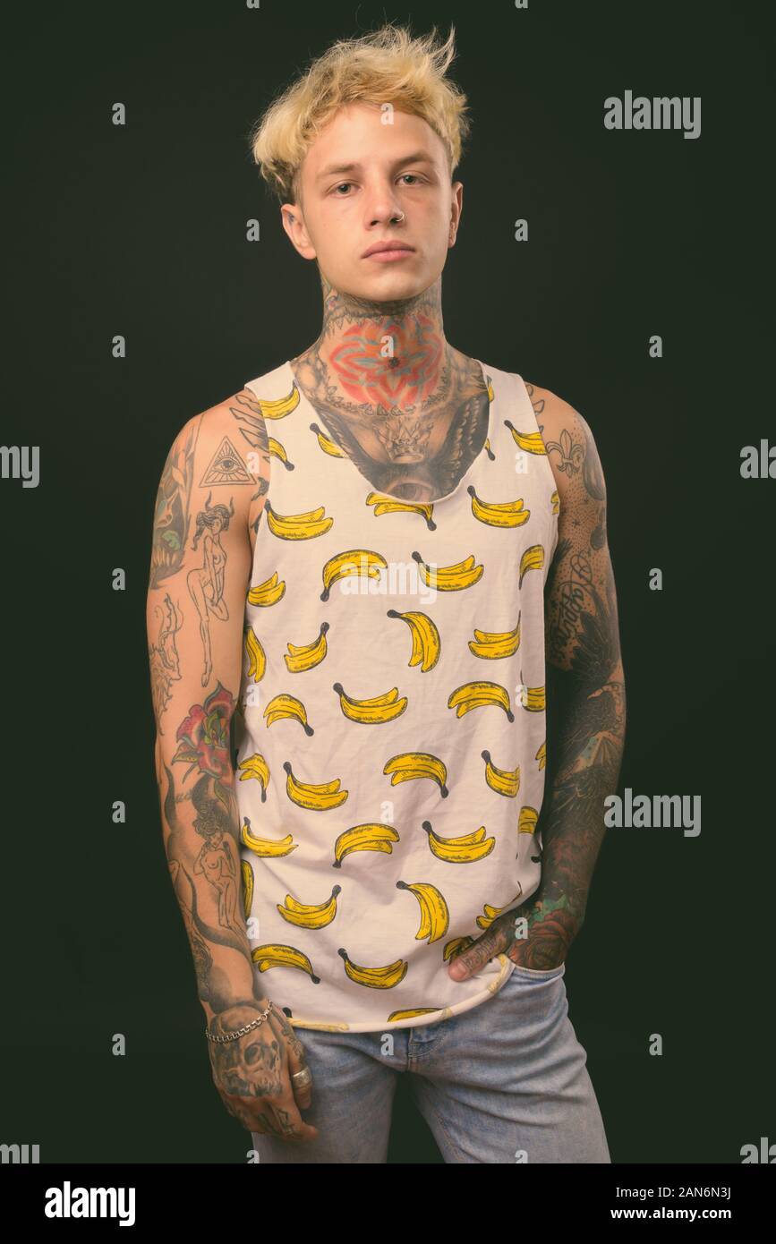 Beau jeune homme rebelle aux cheveux blonds sur fond noir Banque D'Images