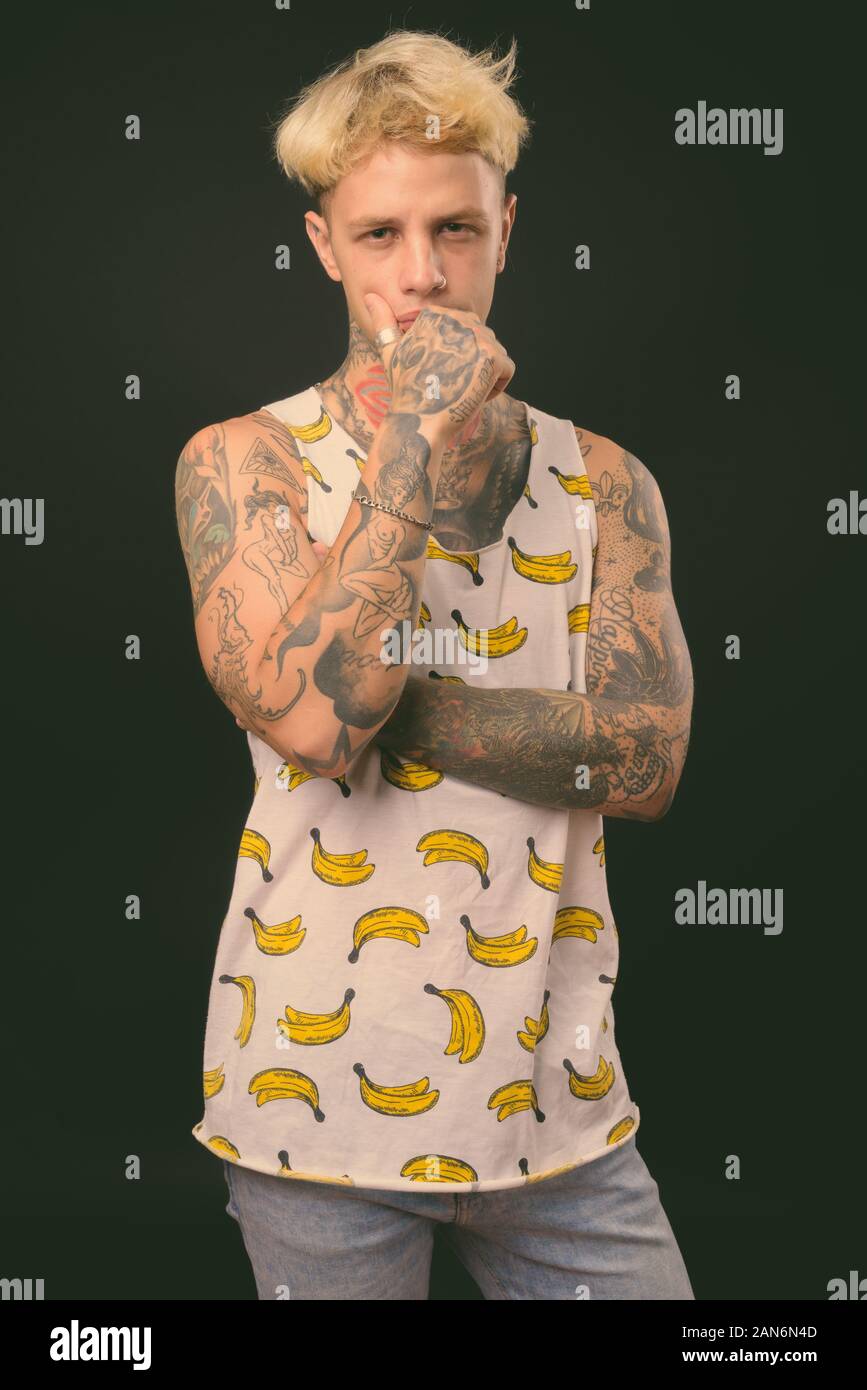 Beau jeune homme rebelle aux cheveux blonds sur fond noir Banque D'Images