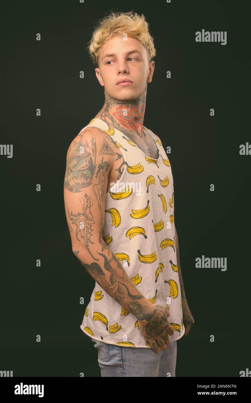 Beau jeune homme rebelle aux cheveux blonds sur fond noir Banque D'Images