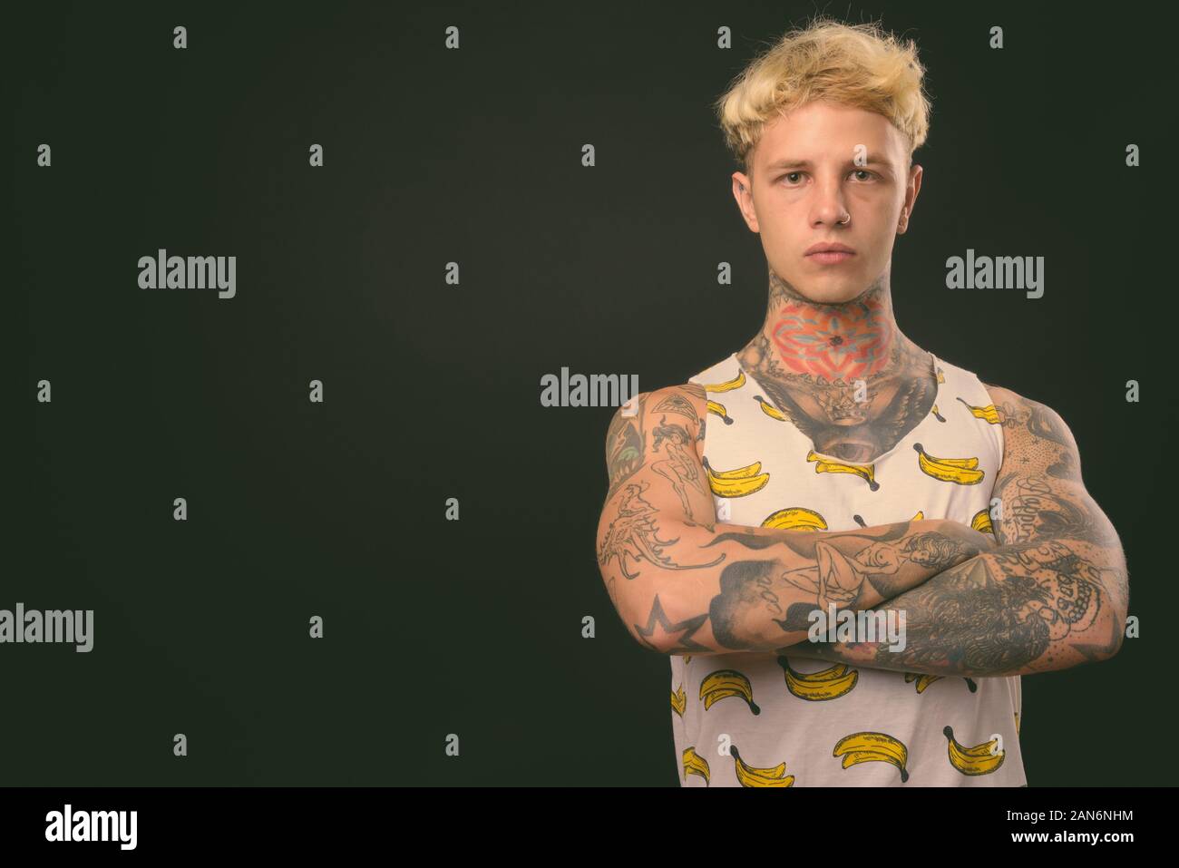 Beau jeune homme rebelle aux cheveux blonds sur fond noir Banque D'Images