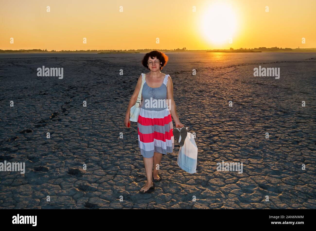 Femme adulte est à fond d'un lac salé desséché contre l'arrière-plan d'un soir le coucher du soleil Banque D'Images