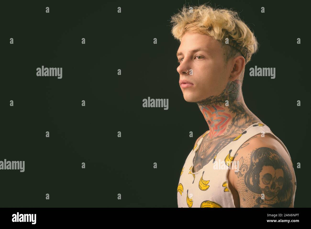 Beau jeune homme rebelle aux cheveux blonds sur fond noir Banque D'Images