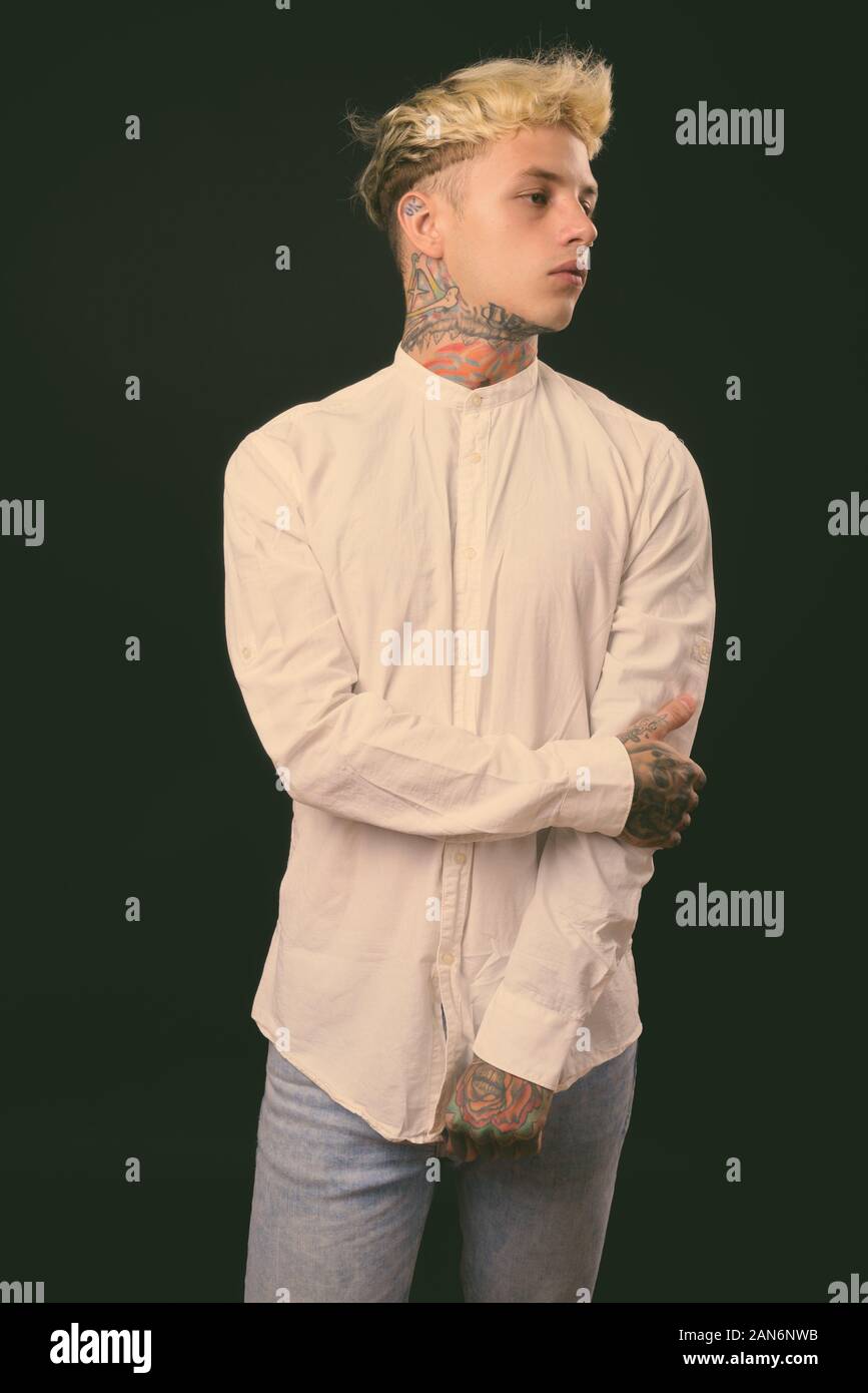 Beau jeune homme rebelle aux cheveux blonds sur fond noir Banque D'Images