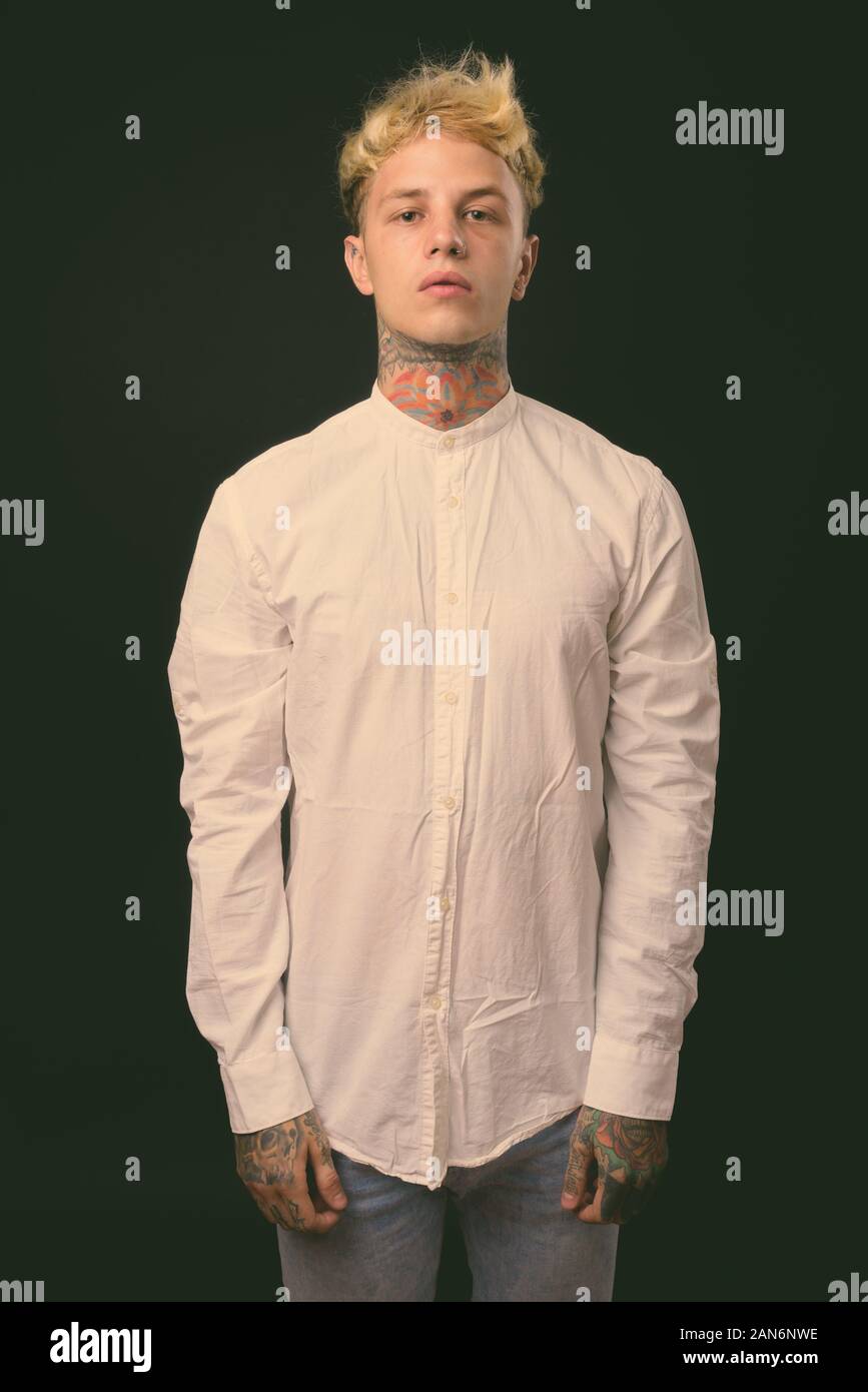 Beau jeune homme rebelle aux cheveux blonds sur fond noir Banque D'Images