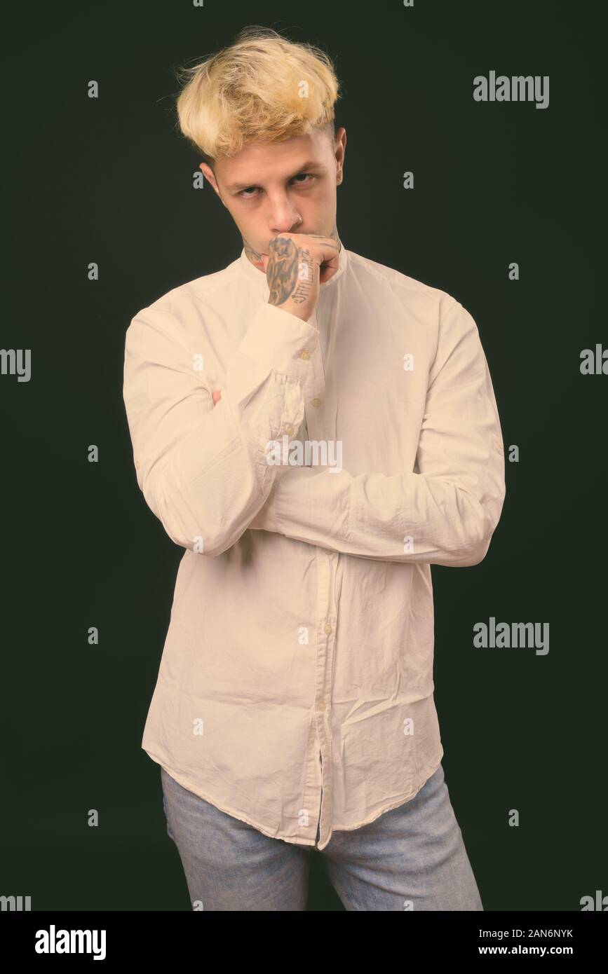 Beau jeune homme rebelle aux cheveux blonds sur fond noir Banque D'Images