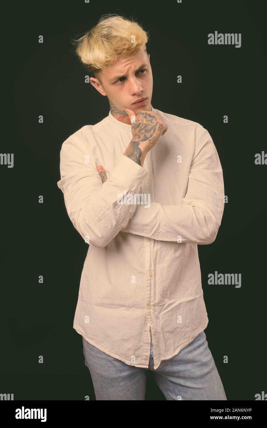 Beau jeune homme rebelle aux cheveux blonds sur fond noir Banque D'Images