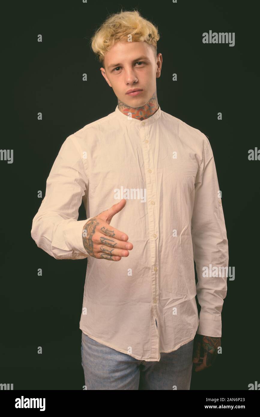 Beau jeune homme rebelle aux cheveux blonds sur fond noir Banque D'Images