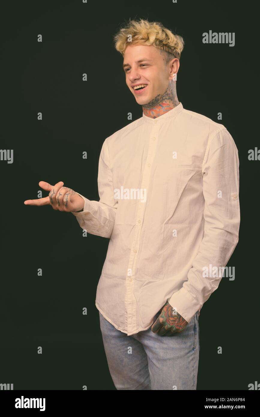 Beau jeune homme rebelle aux cheveux blonds sur fond noir Banque D'Images